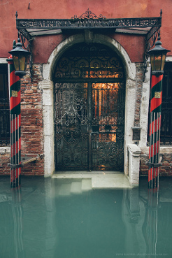 A black steel arched doorway with water outside.